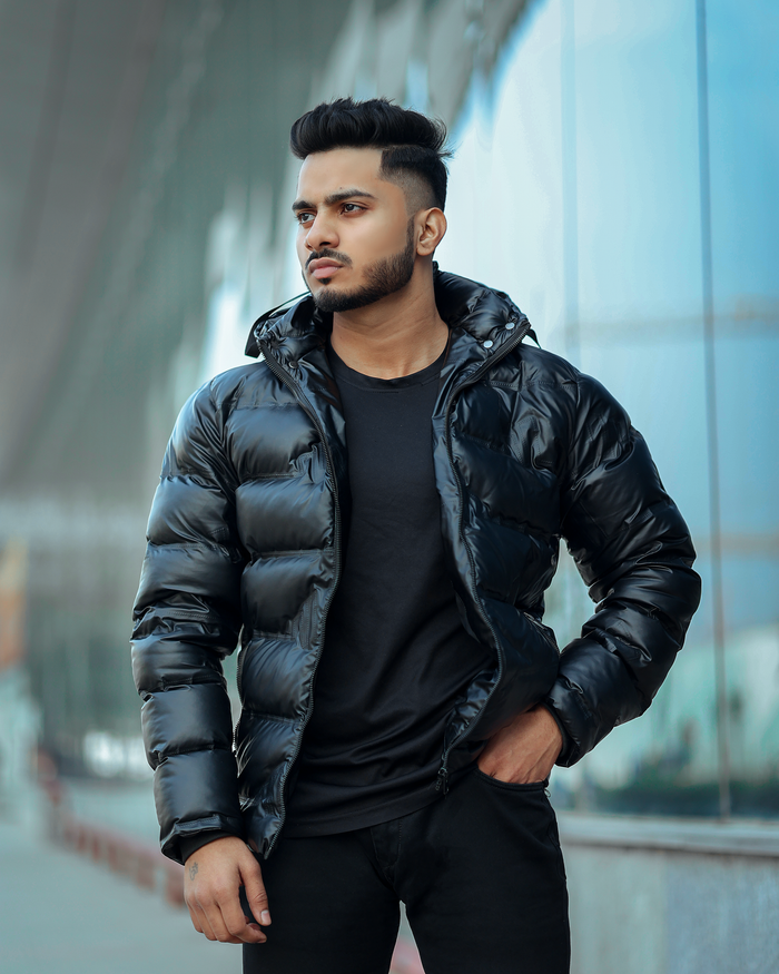 Home Portrait of a young man in a black winter jacket posing outdoors, exemplifying modern fashion.