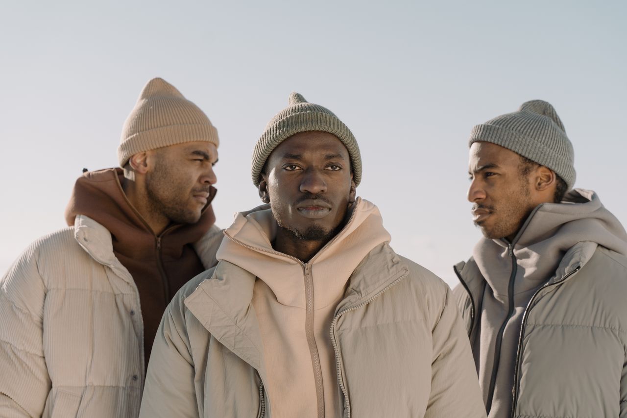 Home Three men in stylish winter attire showcasing modern fashion trends outdoors.